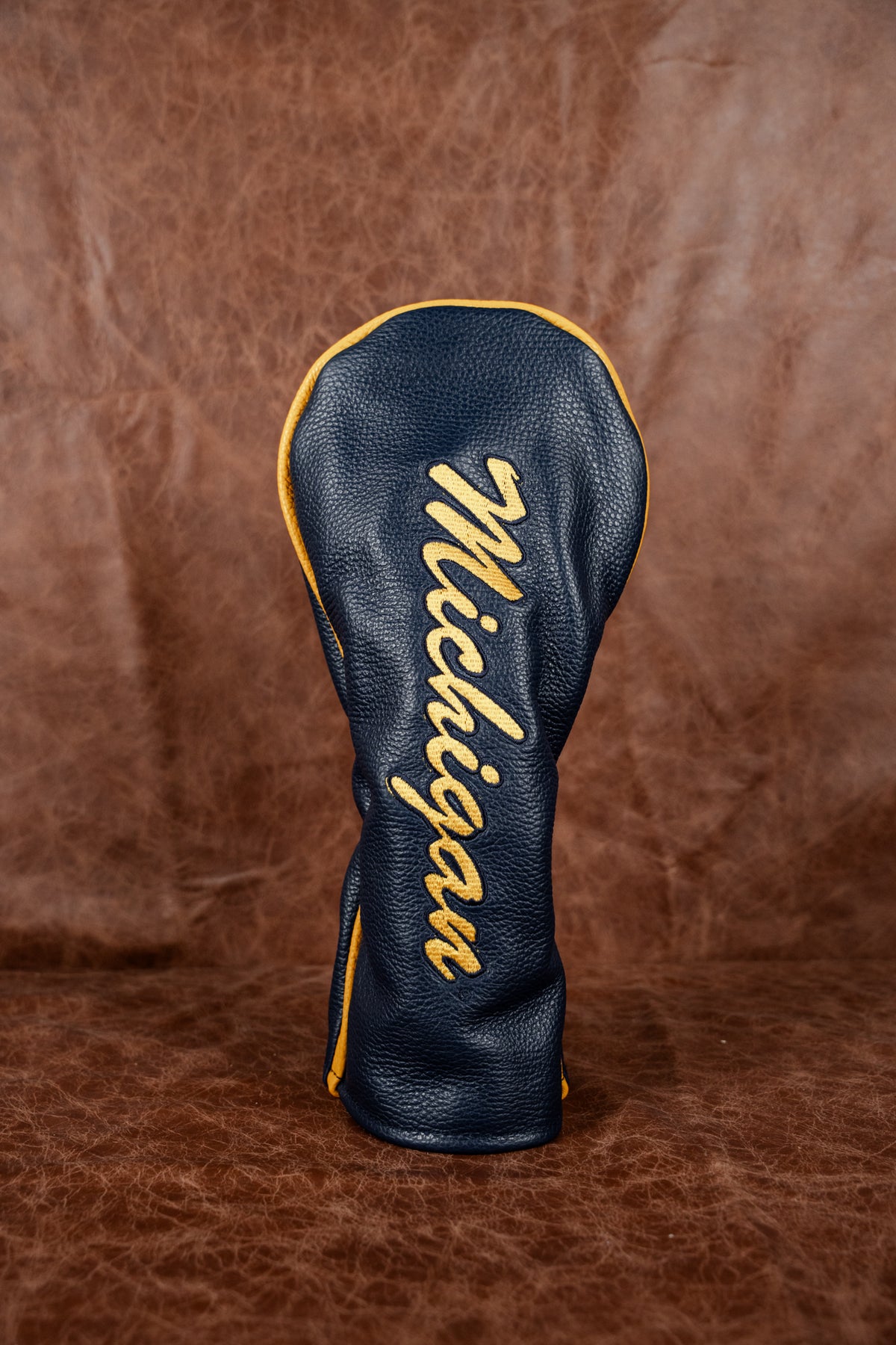Black suede iliac valuables pouch clipped to a golf bag in evening light