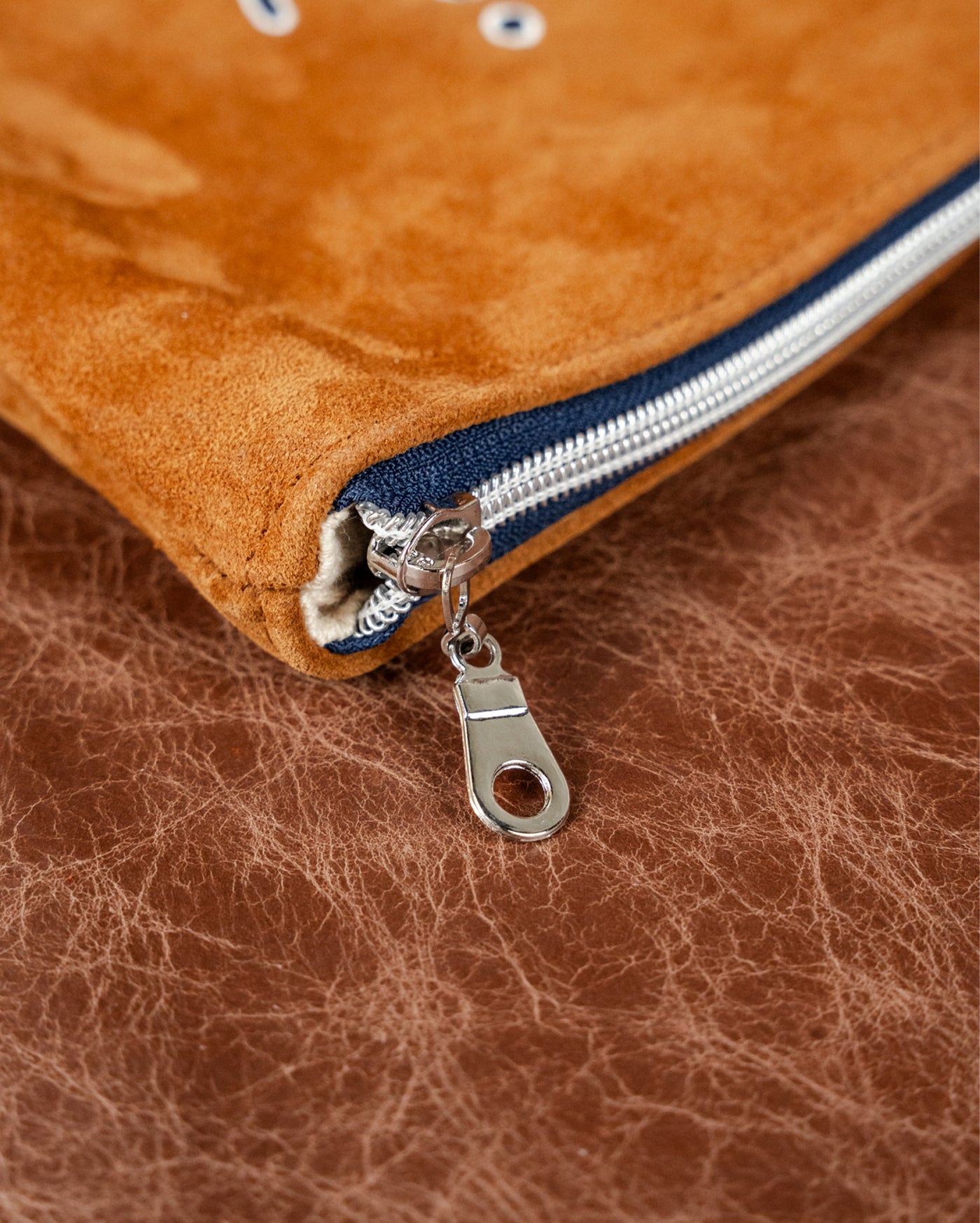 Close-up of navy zipper and pull on the caramel suede Velora Fall Edition clutch