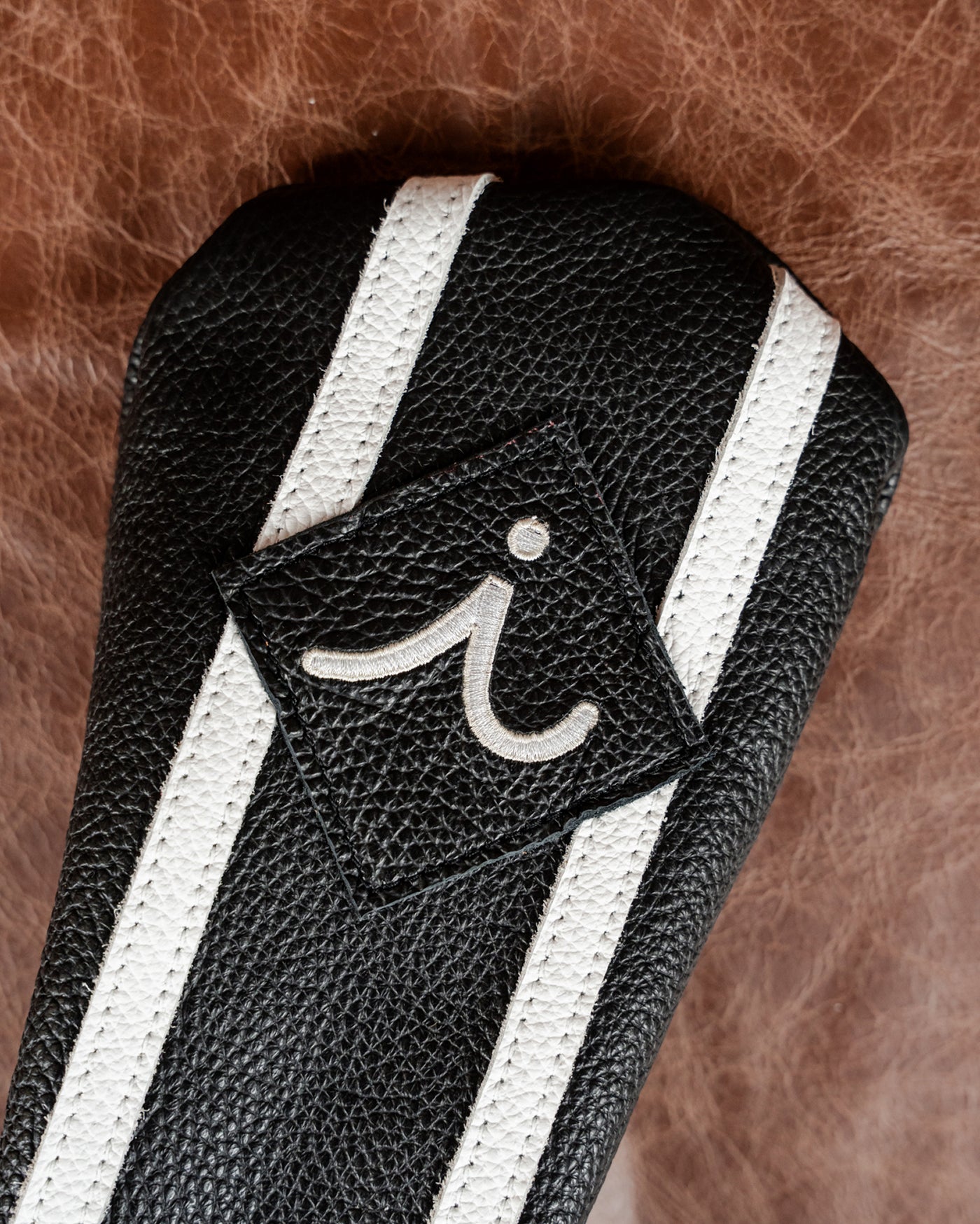 Driver. Close-up of embroidered i on iliac Tuxedo striped leather headcover
