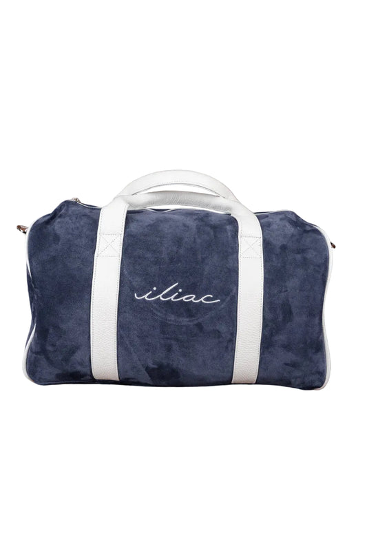 Navy blue duffel bag with white handle and 'iliac' branding on a brown textured background